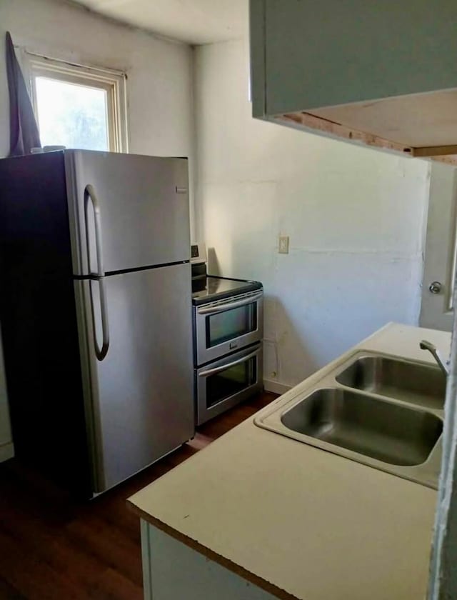 kitchen with dark wood finished floors, stainless steel appliances, a sink, and light countertops