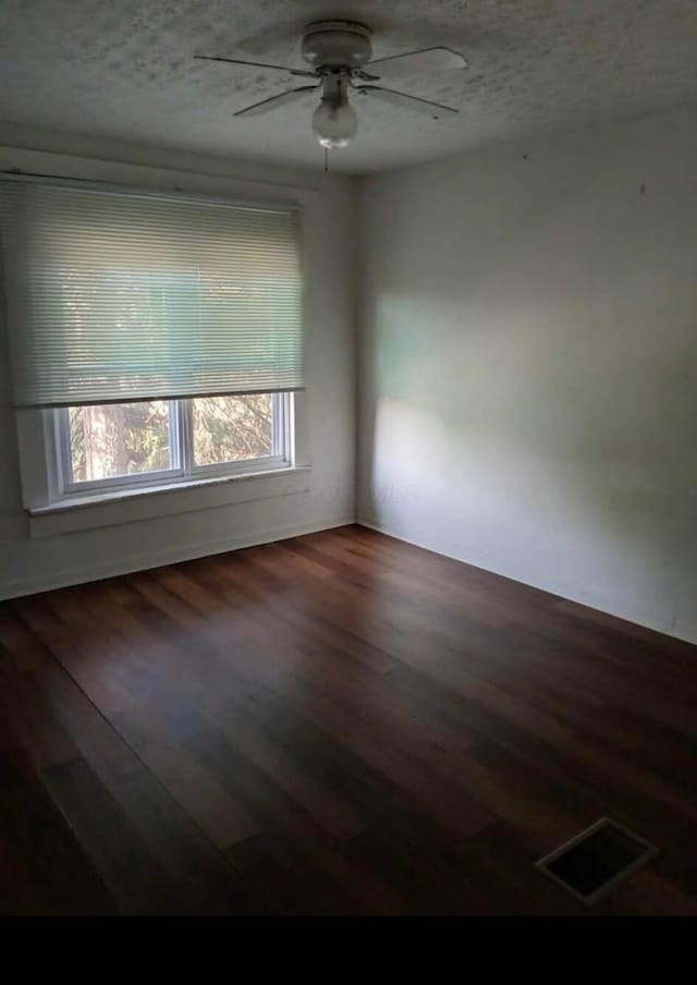 empty room featuring a textured ceiling, wood finished floors, and visible vents