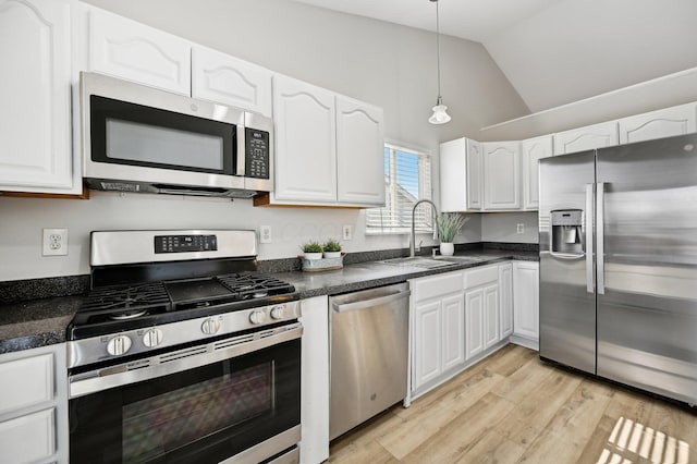 kitchen with white cabinetry, dark countertops, appliances with stainless steel finishes, and a sink