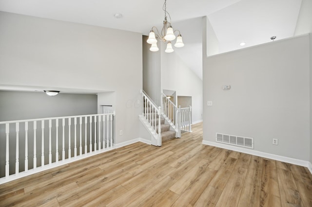 unfurnished room featuring visible vents, high vaulted ceiling, a notable chandelier, wood finished floors, and baseboards