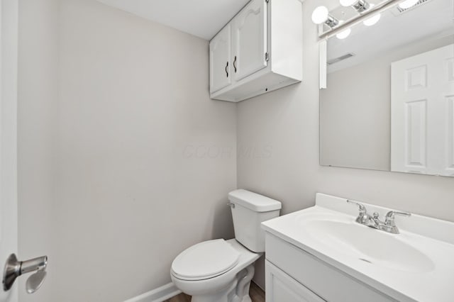 bathroom featuring vanity, toilet, baseboards, and visible vents