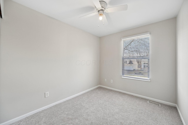 carpeted empty room featuring a ceiling fan, visible vents, and baseboards