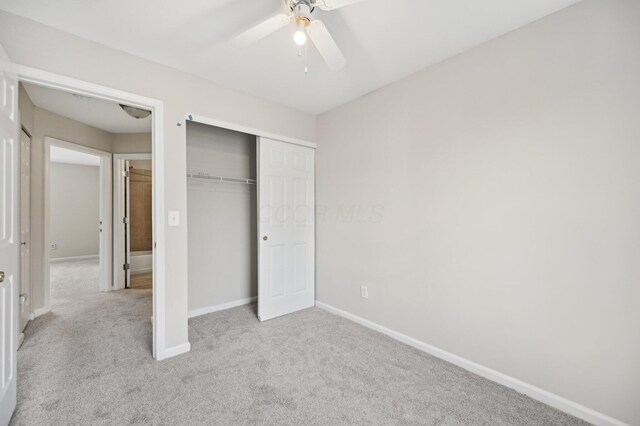 unfurnished bedroom with light carpet, ceiling fan, a closet, and baseboards