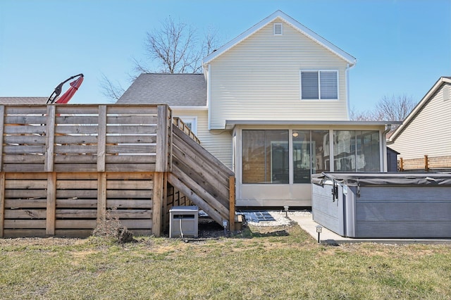 back of house featuring a shingled roof, a hot tub, stairs, a lawn, and a sunroom