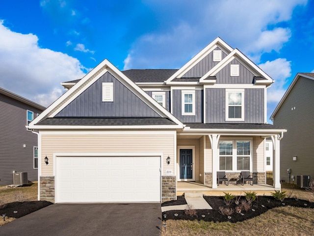 craftsman inspired home featuring central air condition unit, stone siding, driveway, and board and batten siding