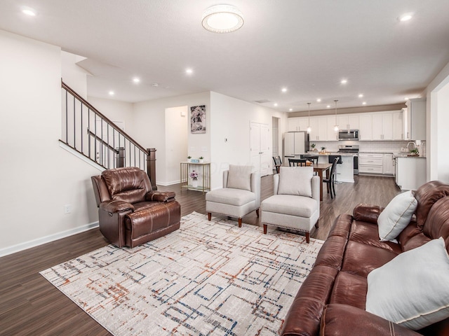 living room with stairs, baseboards, and dark wood-style flooring