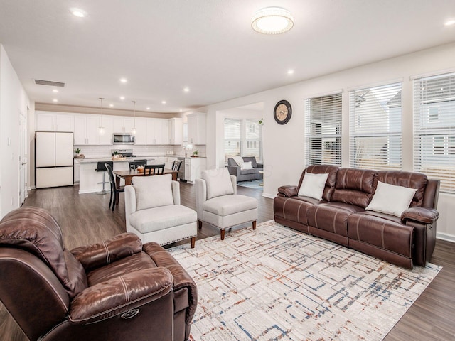 living area with recessed lighting, visible vents, plenty of natural light, and wood finished floors