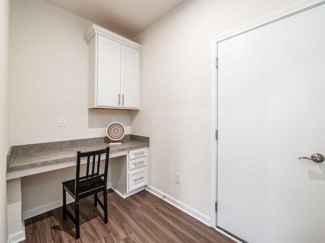 office area with dark wood finished floors, built in desk, and baseboards