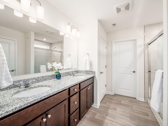 full bath featuring double vanity, a stall shower, a sink, and visible vents