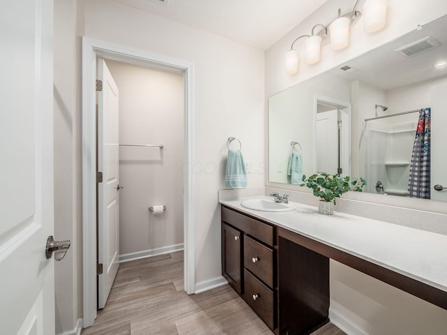 bathroom with visible vents, a shower with shower curtain, vanity, wood finished floors, and baseboards