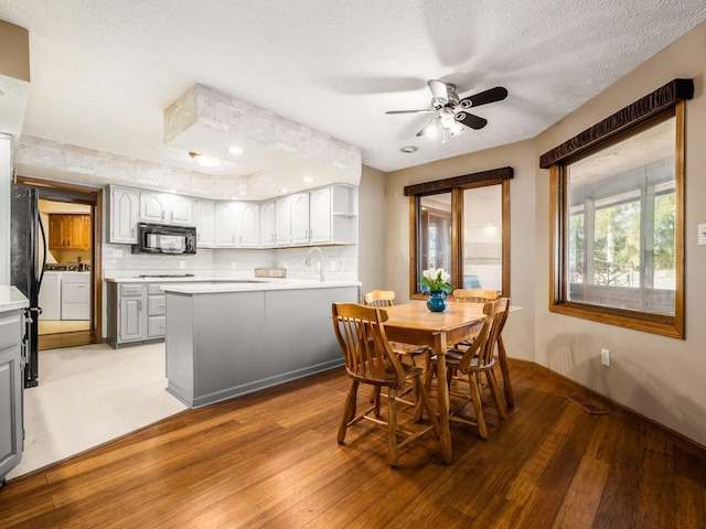 dining room featuring baseboards, ceiling fan, light wood-style flooring, and a textured ceiling