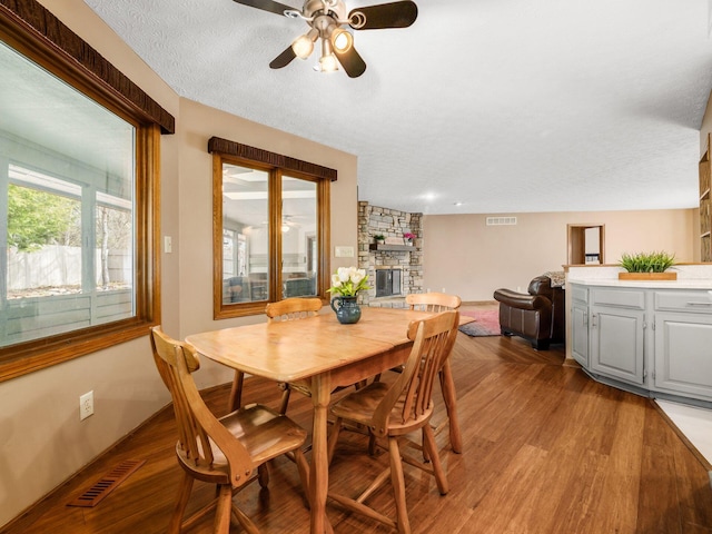 dining area featuring light wood-type flooring, visible vents, a fireplace, and a textured ceiling