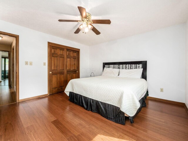 bedroom with a closet, wood finished floors, and baseboards