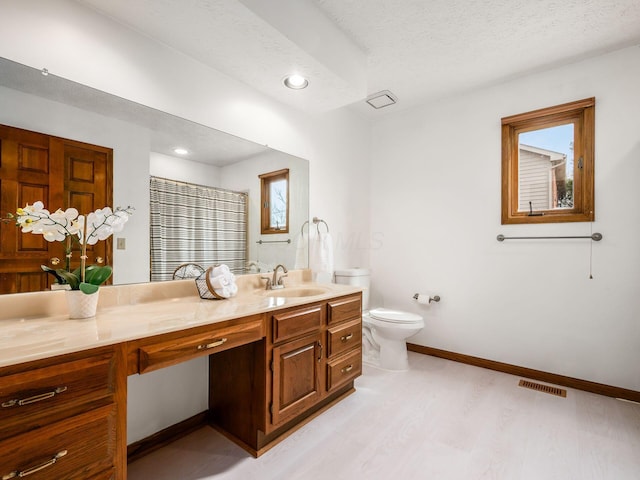 full bath with visible vents, toilet, vanity, wood finished floors, and baseboards