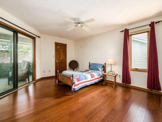 bedroom with access to exterior, a textured ceiling, baseboards, and wood finished floors