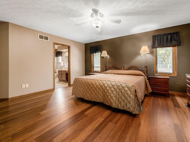 bedroom with visible vents, a textured ceiling, baseboards, and wood finished floors