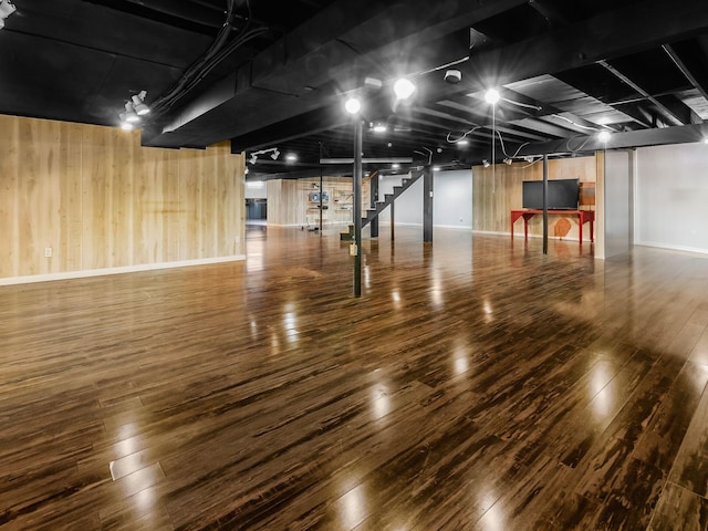 below grade area featuring wood-type flooring, wooden walls, and baseboards