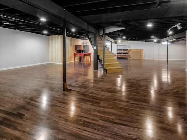 finished basement with baseboards, stairway, and wood finished floors