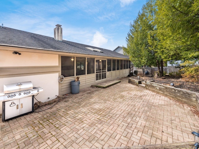 rear view of property with a patio, a chimney, fence, and a sunroom