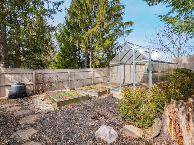 view of yard with a vegetable garden, fence, a greenhouse, and an outdoor structure