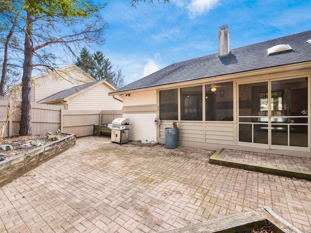 rear view of house with a shingled roof, a patio area, fence, and a chimney