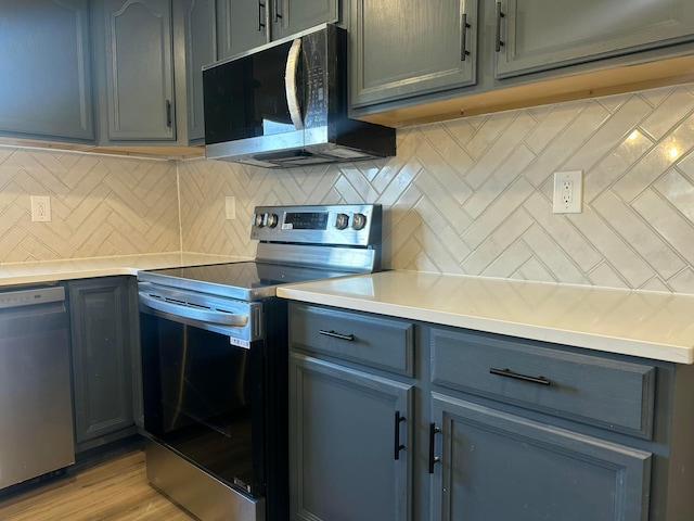 kitchen with light countertops, light wood-style flooring, tasteful backsplash, and stainless steel appliances