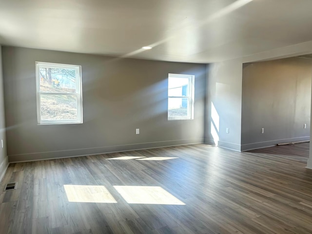 spare room with visible vents, baseboards, and wood finished floors