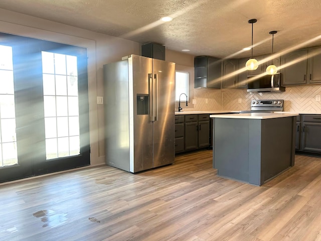 kitchen with a wealth of natural light, light wood-type flooring, stainless steel appliances, light countertops, and decorative backsplash