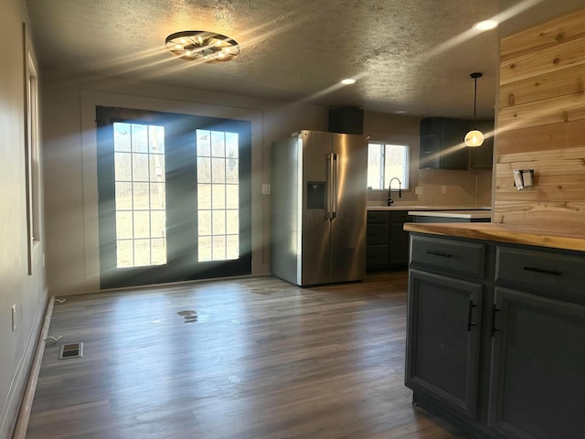 kitchen featuring visible vents, dark wood-type flooring, a sink, stainless steel fridge, and wooden counters