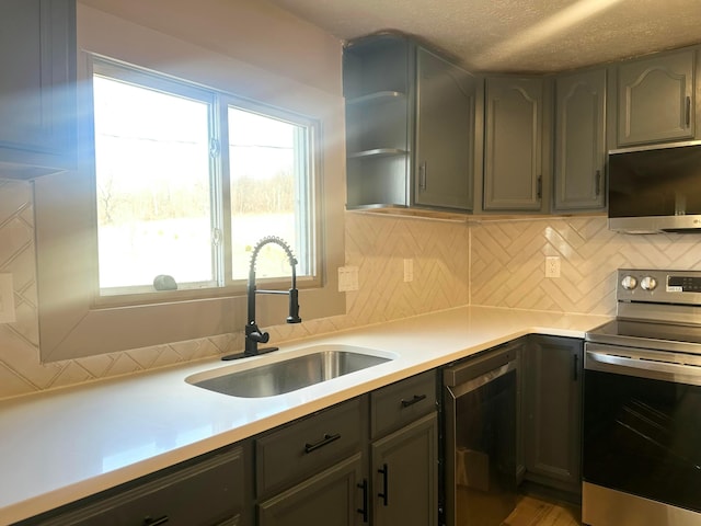 kitchen with a sink, light countertops, decorative backsplash, stainless steel appliances, and open shelves