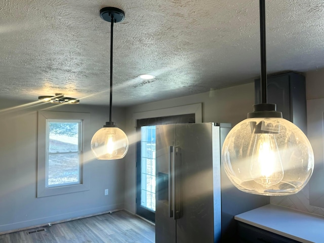 kitchen featuring visible vents, high end fridge, a textured ceiling, and light wood-type flooring