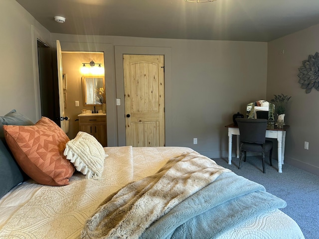 carpeted bedroom featuring ensuite bath and baseboards