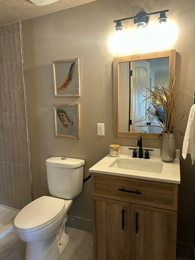 full bathroom featuring tile patterned flooring, baseboards, toilet, a tile shower, and vanity