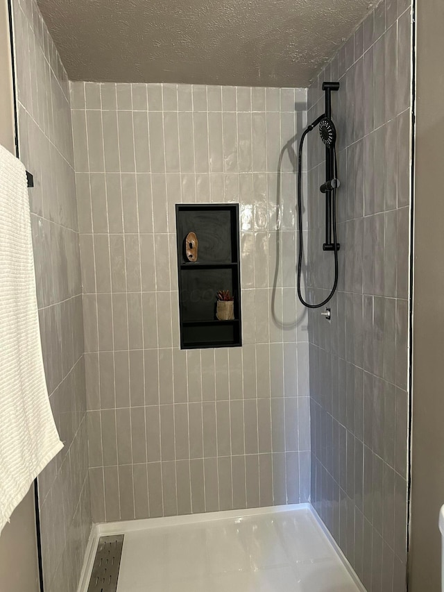 bathroom featuring a tile shower and a textured ceiling