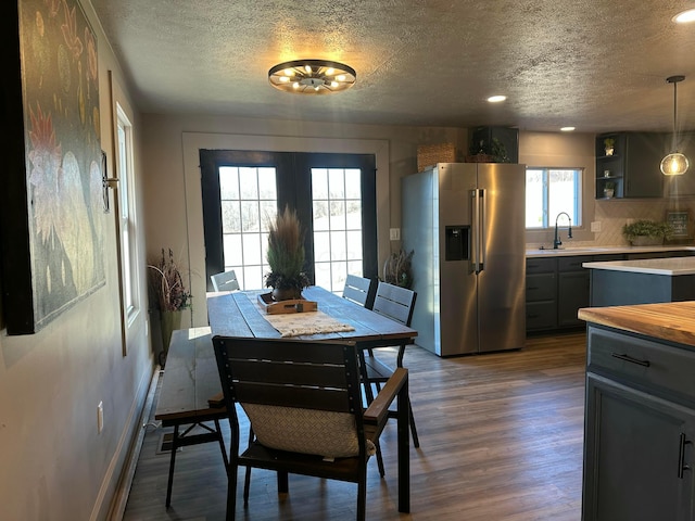 dining area featuring a textured ceiling, dark wood-style floors, recessed lighting, french doors, and baseboards