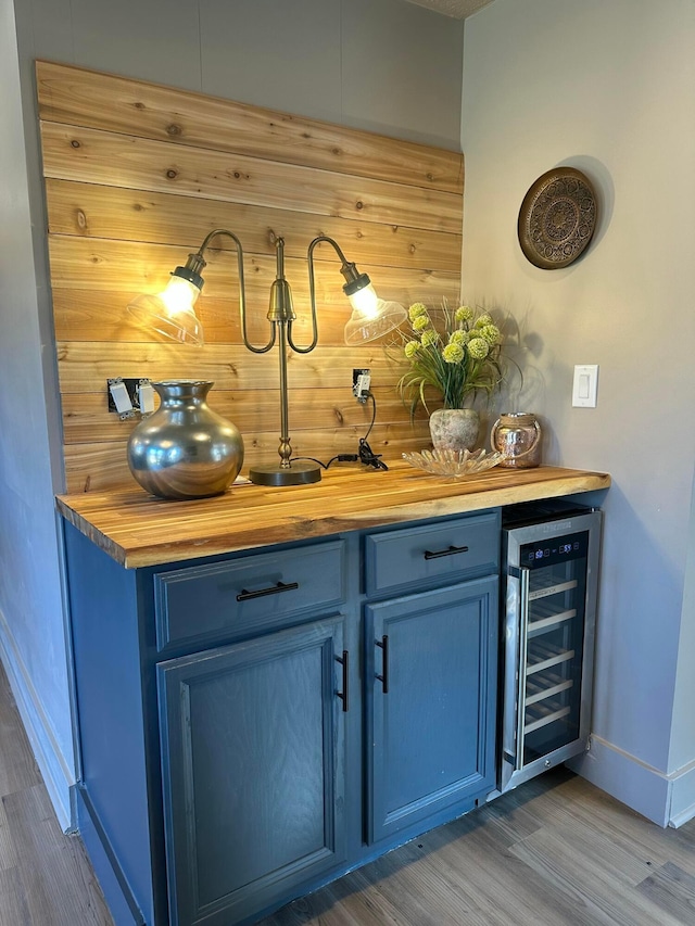 bar with wood finished floors, a dry bar, beverage cooler, and baseboards