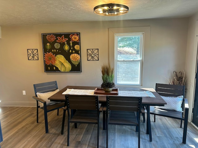 dining room with an inviting chandelier, wood finished floors, baseboards, and a textured ceiling