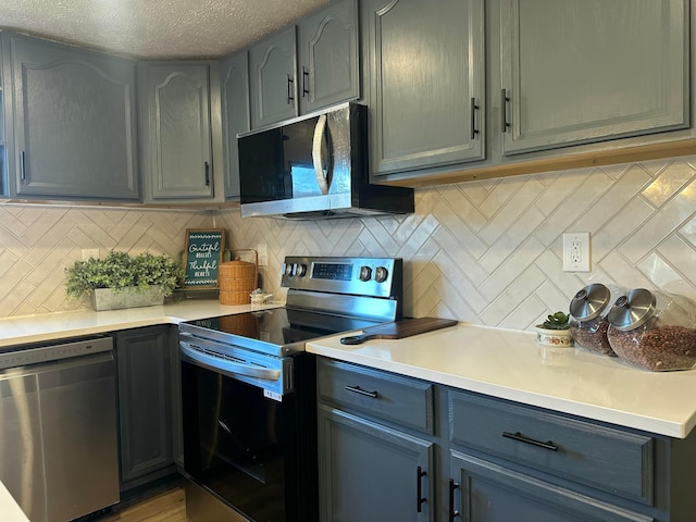 kitchen with tasteful backsplash, a textured ceiling, stainless steel appliances, and light countertops