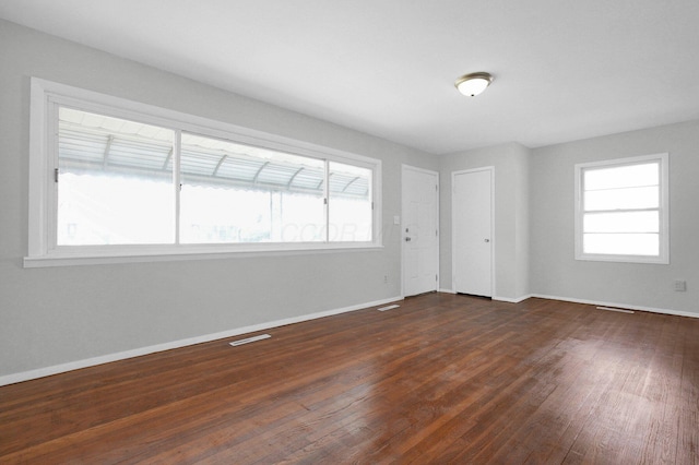 empty room featuring visible vents, baseboards, and dark wood-style floors