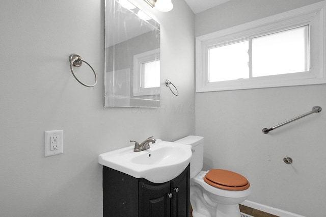 bathroom featuring toilet, vanity, and baseboards