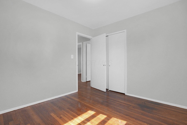 empty room featuring dark wood-style floors and baseboards