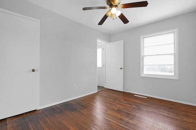 unfurnished room with hardwood / wood-style floors, visible vents, baseboards, and ceiling fan