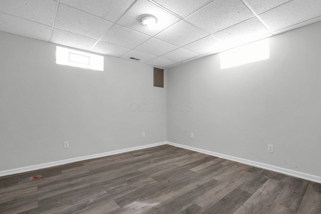 below grade area featuring dark wood finished floors, visible vents, baseboards, and a drop ceiling