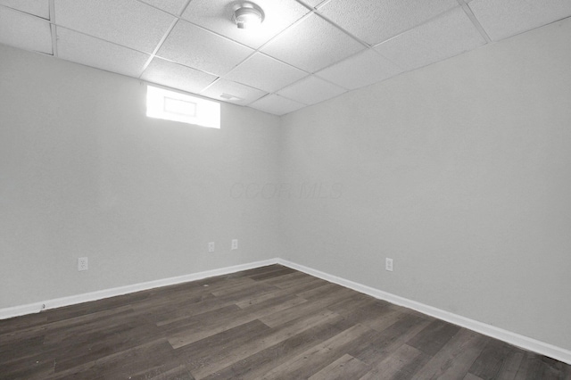 below grade area with baseboards, a paneled ceiling, and dark wood-type flooring