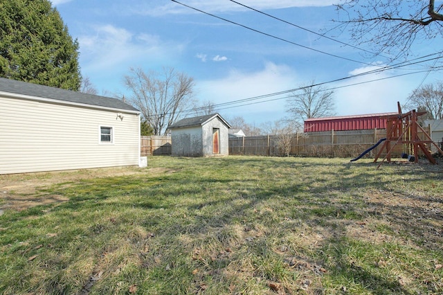 view of yard featuring an outdoor structure, a playground, a storage unit, and a fenced backyard