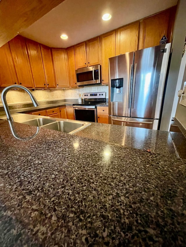 kitchen with tasteful backsplash, brown cabinets, stainless steel appliances, a sink, and recessed lighting