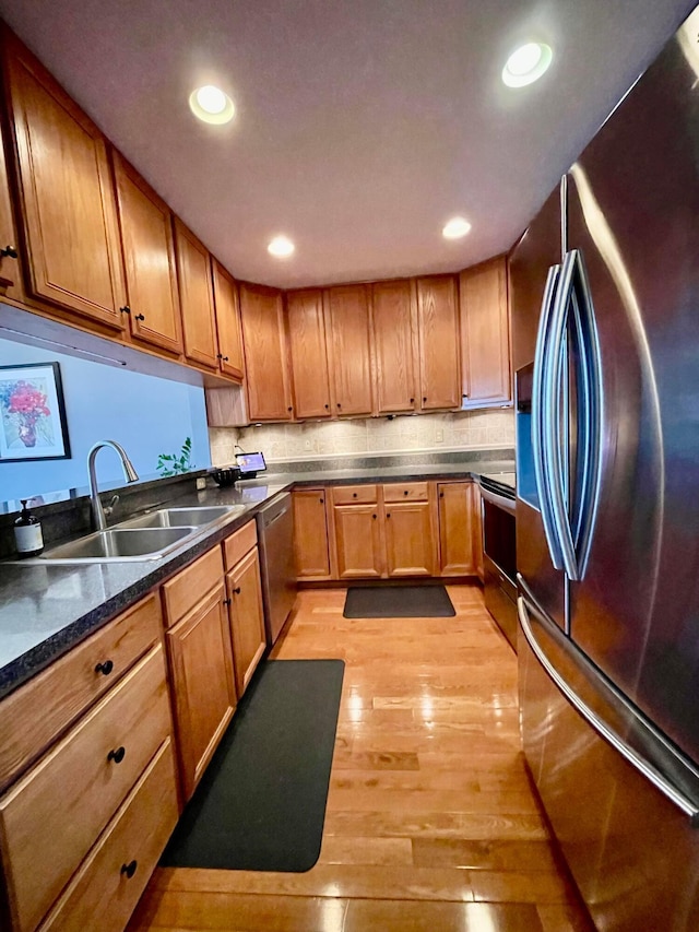 kitchen featuring recessed lighting, a sink, appliances with stainless steel finishes, brown cabinets, and light wood finished floors