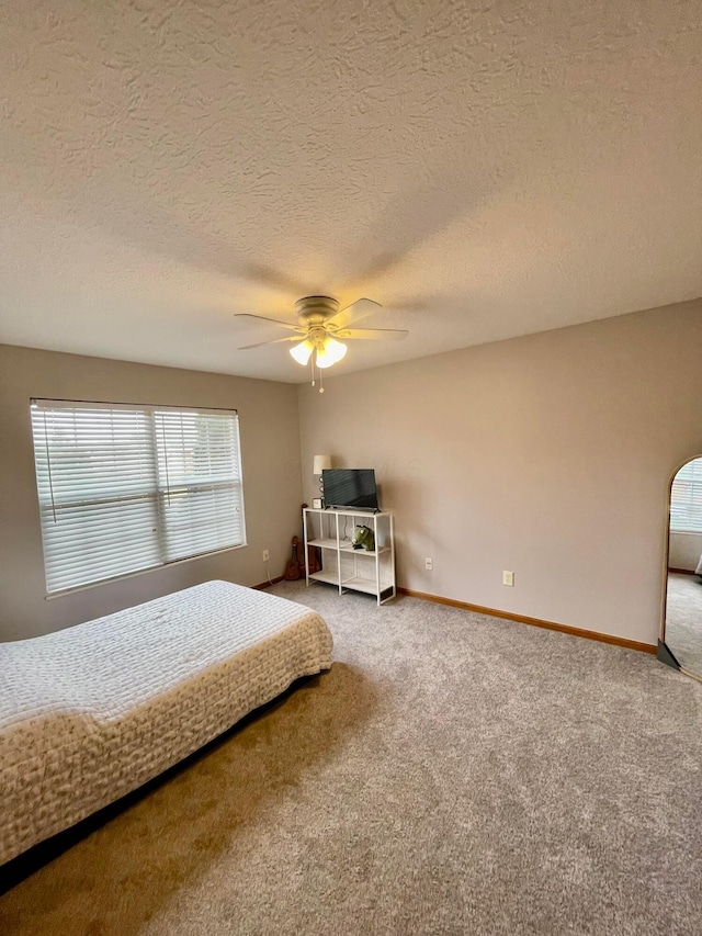 carpeted bedroom with ceiling fan, a textured ceiling, and baseboards