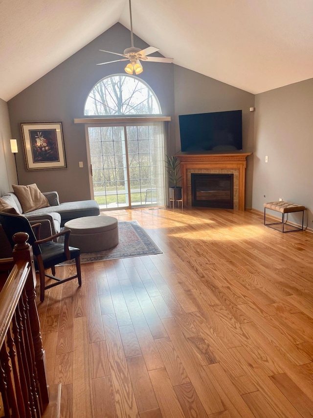 living room with ceiling fan, high vaulted ceiling, a fireplace, and wood finished floors