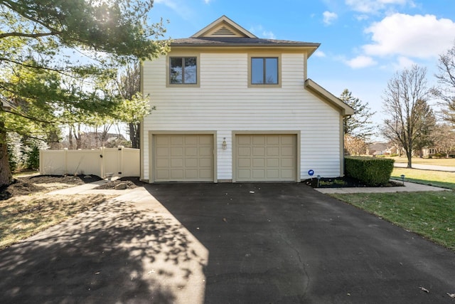 view of front facade featuring driveway, an attached garage, and fence